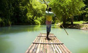 Bamboo rafting on the Martha Brae River in Falmouth, Jamaica with a guide steering the raft.