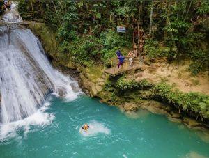 Guests jumping into turquoise pool at Island Gully Falls Blue Hole in Ocho Rios, Jamaica.